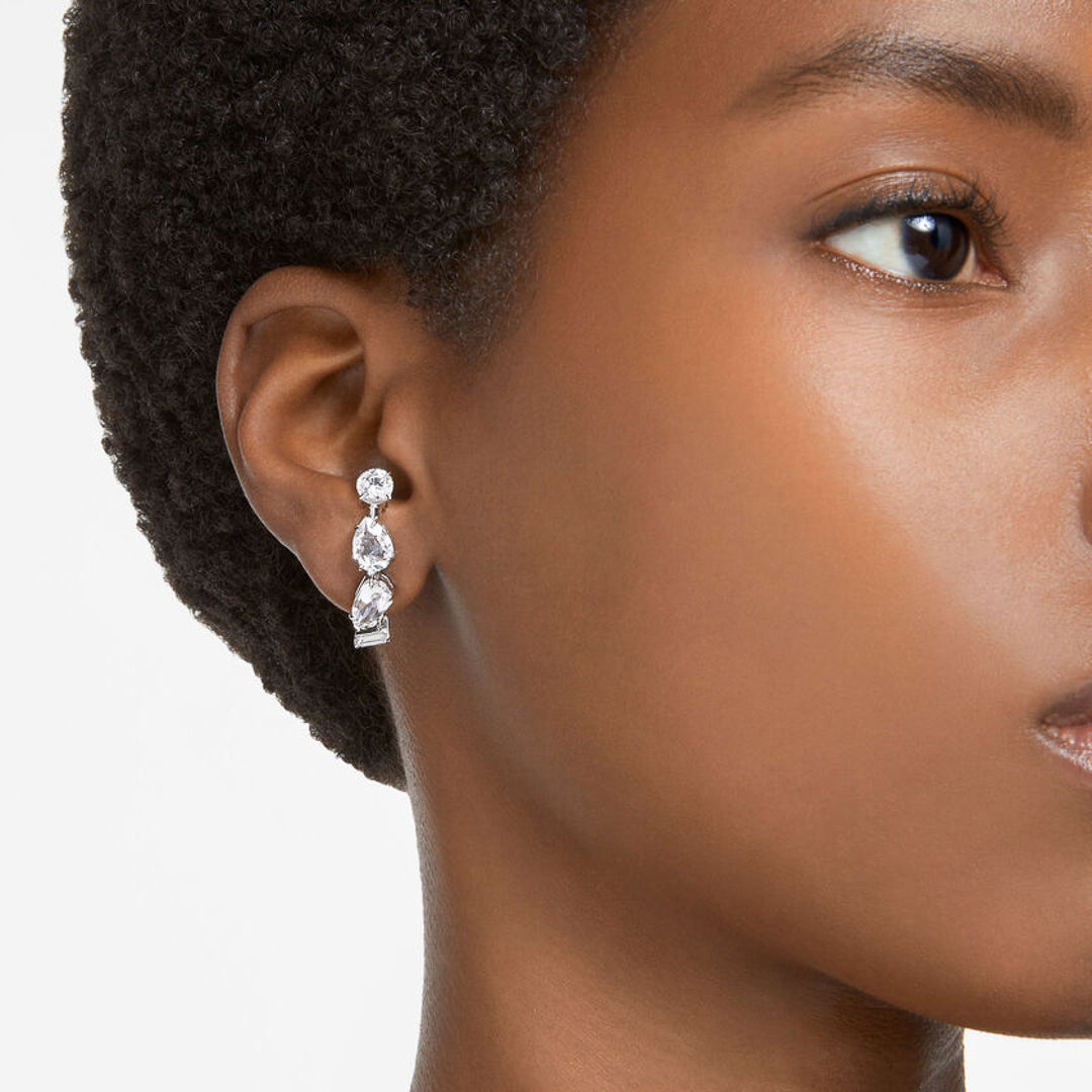 A close-up of a person wearing the stunning Swarovski Gema Ear Cuffs, featuring three large stones with clear crystal cuts arranged vertically. The individual has short, curly hair, and only part of their face is visible against a plain background.