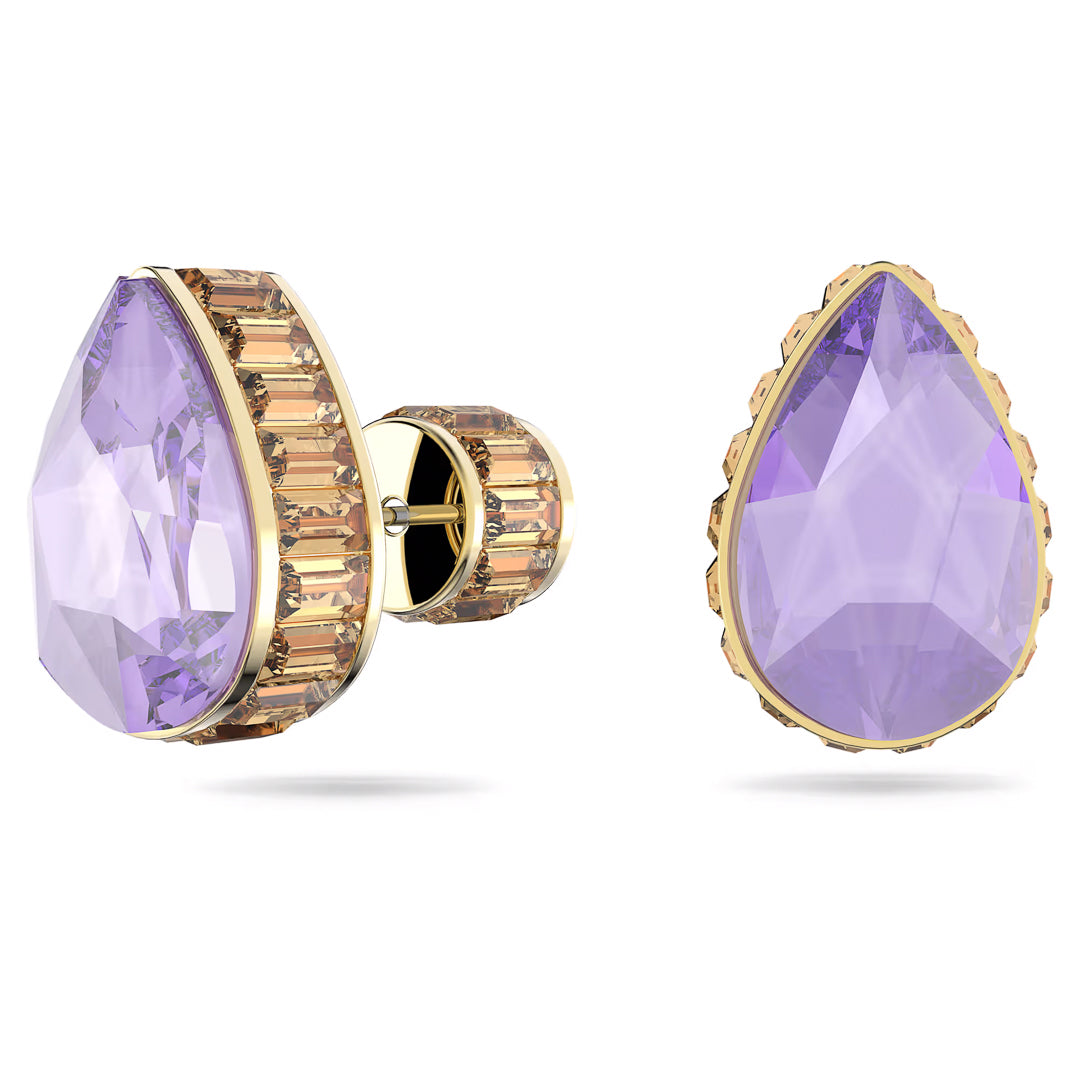 As part of the Swarovski Chroma Stud Earrings collection by Swarovski, these teardrop-shaped earrings feature prominent faceted lavender gemstones set in gold, accented with smaller baguette-cut stones along the edges. The left earring is presented from a side perspective, while the right earring is displayed from a frontal view.