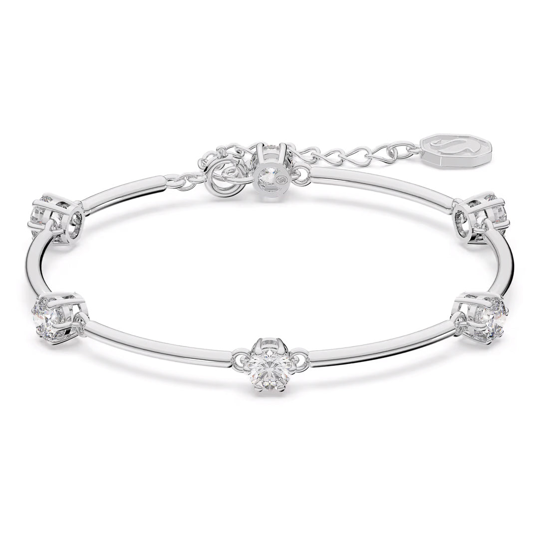 A silver bracelet with a delicate chain design, adorned with a series of clear, sparkling zirconia gemstones along its length. It's rhodium plated for additional shine and features an adjustable clasp alongside a small engraved tag that evokes the sophisticated charm of the Swarovski Constella Bangle.