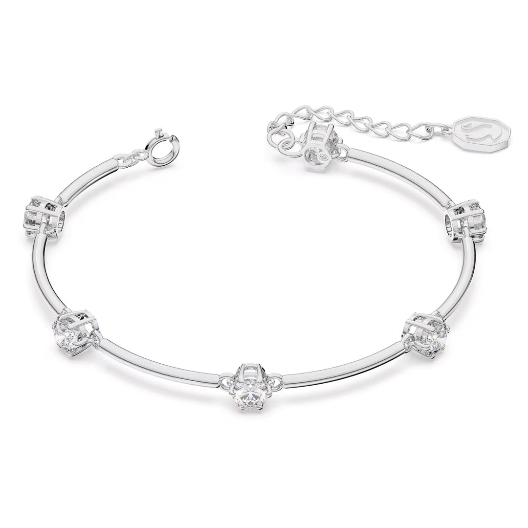 The Swarovski Constella Bangle is a delicate piece adorned with rhodium-plated silver, featuring a series of evenly spaced small, sparkling zirconia gemstones connected by slender, curved silver bars. It comes with an adjustable chain and a small tag at the clasp for size customization.
