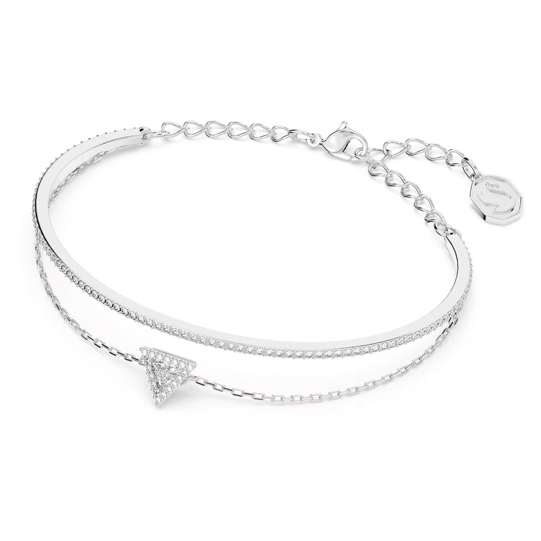 Introducing the Swarovski Stilla Bracelet by Swarovski: a refined rhodium-plated bangle accompanied by a chain, which showcases a stunning triangle-cut crystal pendant adorned with smaller crystals. This elegant accessory comes with an adjustable chain clasp and a branded charm, adding an extra touch of sophistication.