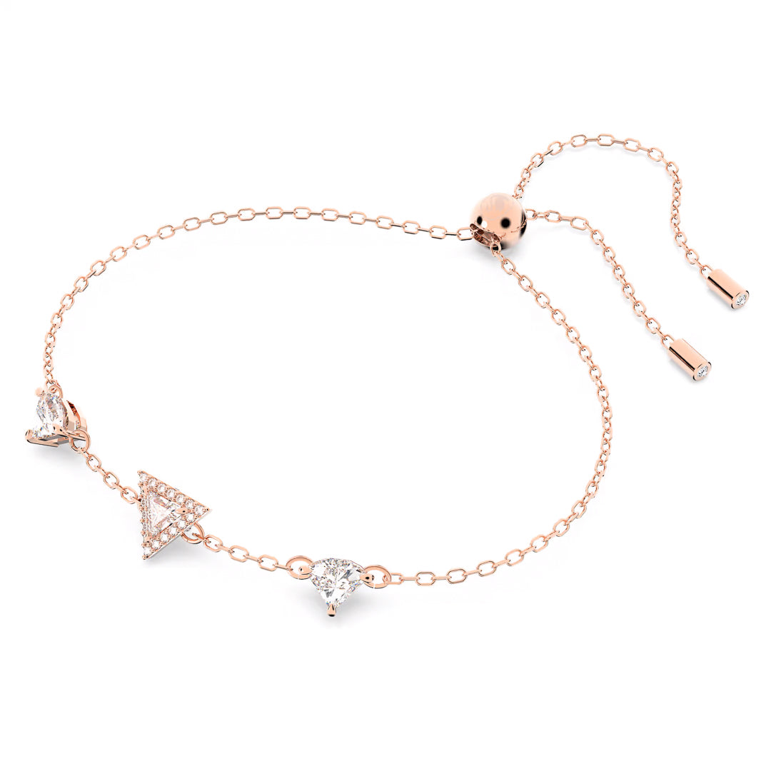 The Swarovski Stilla Bracelet showcases a minimalist rose gold-tone chain featuring an adjustable sliding clasp. This elegant design is enhanced with three diamond-studded charms in the shape of a triangle, a circle, and a heart, complemented by small matching accents at the ends.