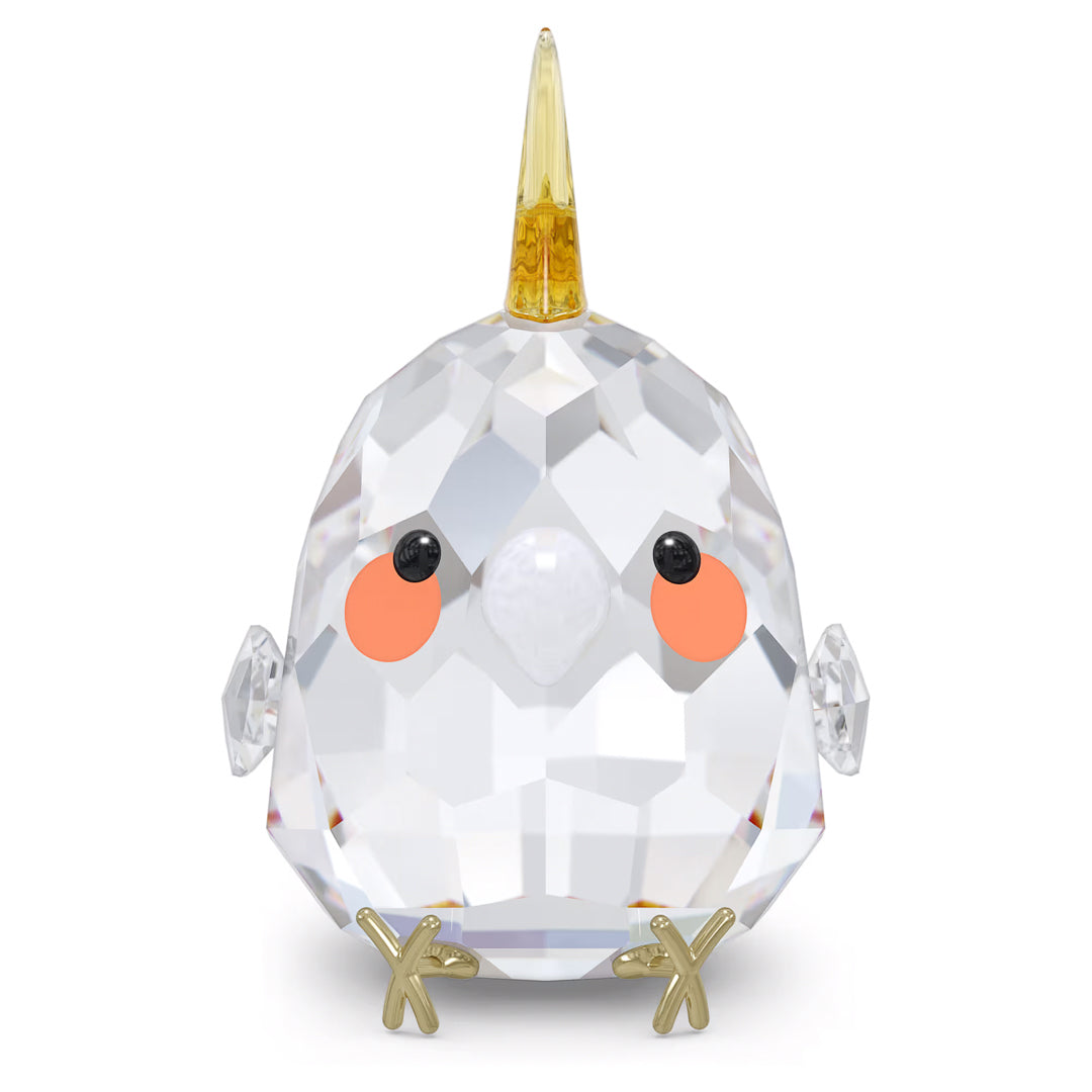 This delightful gift, the Swarovski All you Need are Birds Yellow Cockatiel Home Décor by Swarovski, is a faceted crystal cockatiel figurine adorned with a gold horn on its head, orange cheeks, and small black eyes. Its outstretched wings and gold feet give it a whimsical unicorn-like charm, showcasing an elegant crystal design.