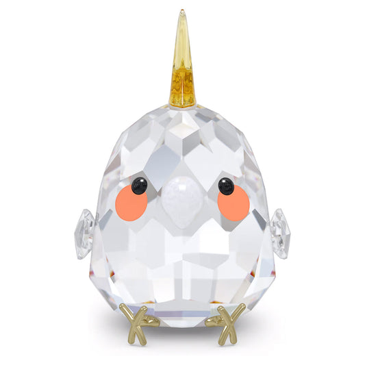 This delightful gift, the Swarovski All you Need are Birds Yellow Cockatiel Home Décor by Swarovski, is a faceted crystal cockatiel figurine adorned with a gold horn on its head, orange cheeks, and small black eyes. Its outstretched wings and gold feet give it a whimsical unicorn-like charm, showcasing an elegant crystal design.