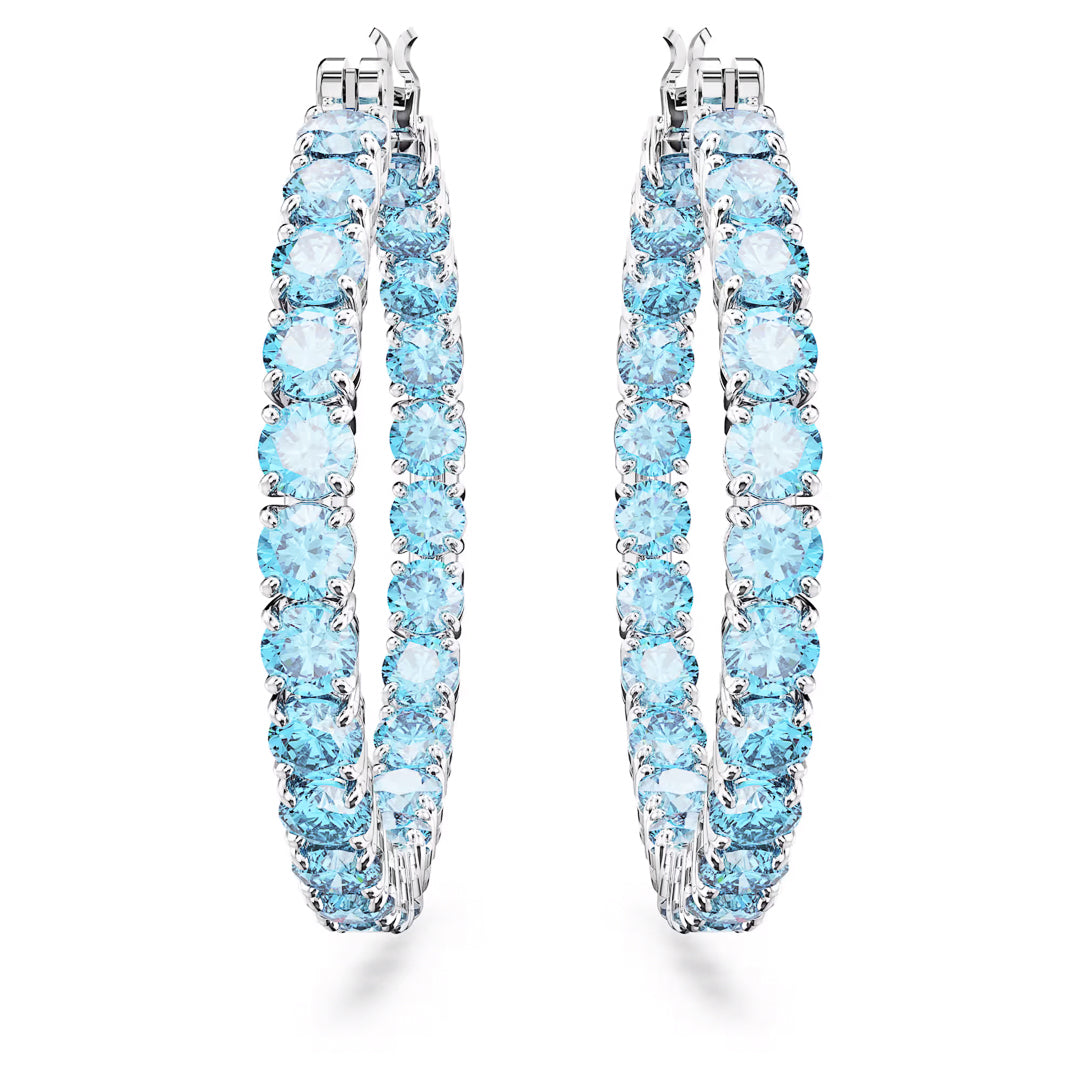 The Swarovski Matrix Hoop Earrings by Swarovski boast a luxurious and elegant design, featuring rhodium-plated matrix hoops adorned with round, sparkling blue zirconia gemstones that encircle the entire hoop.