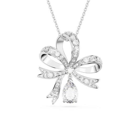 The Swarovski Volta Large Bow Pendant from the renowned brand Swarovski showcases a silver bow-shaped design adorned with clear crystals, all rhodium plated for a lasting shine. Its centerpiece is a gracefully dangling teardrop-shaped diamond, enhancing the elegance and sparkle of this exquisite piece.