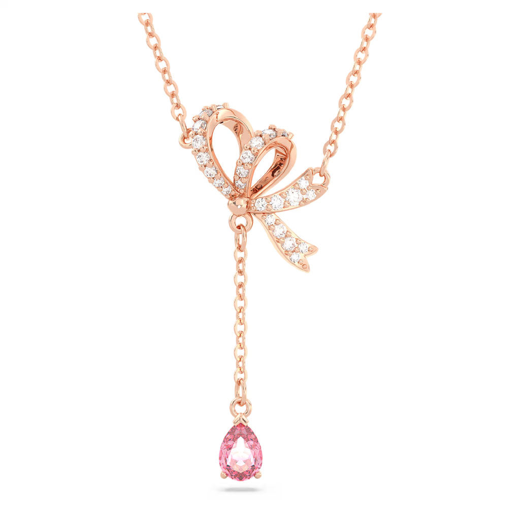 The Swarovski Hyperbola Y Necklace Pendant by Swarovski features a graceful rose gold design with a ribbon-shaped pendant embellished with sparkling diamonds and clear crystals. A single pink teardrop gem elegantly dangles from the pendant, making it an ideal romantic gift.