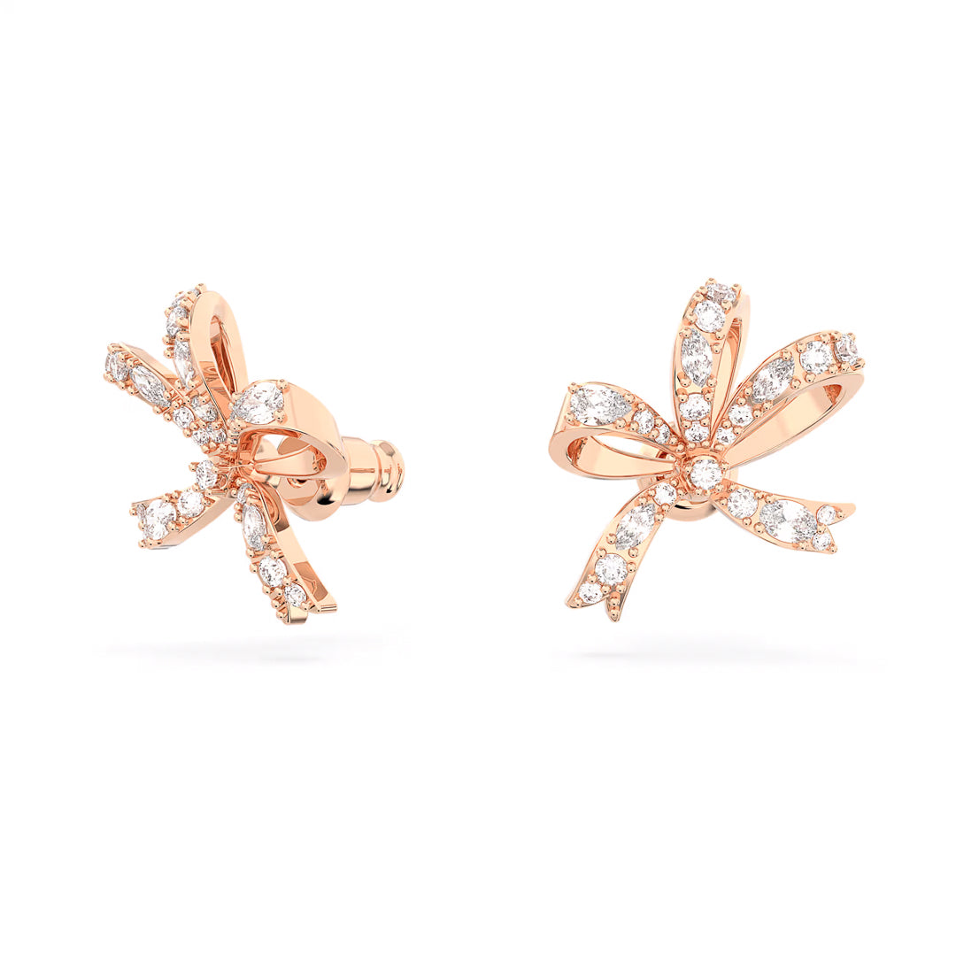 The Swarovski Hyperbola Stud Earrings by Swarovski are crafted in a rose gold-tone plating and feature glowing bow-inspired studs. Adorned with sparkling diamonds and clear crystals, the design showcases intricate loops and elegant curves to enhance the shimmering effect.