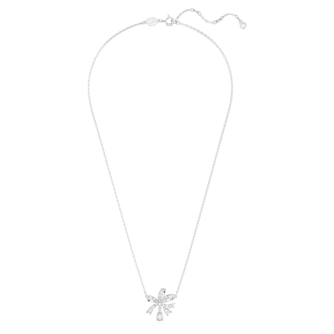 A rhodium-plated silver necklace features a large, ornate ribbon bow pendant adorned with clear crystals, capturing the elegance associated with the Swarovski Hyperbola Necklace Pendant.