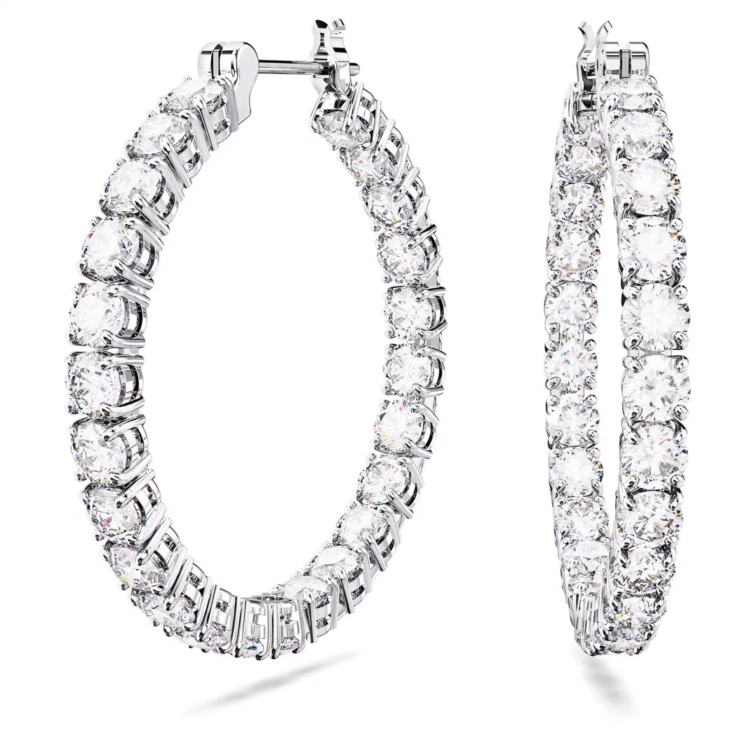 A pair of large, sparkling Swarovski Matrix hoop Earrings adorned with numerous round, clear zirconia gemstones set in rhodium-plated silver. The earrings are positioned vertically side by side, showcasing their intricate design and shimmering appearance against a white background.