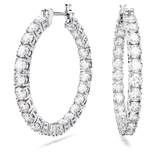 A pair of large, sparkling Swarovski Matrix hoop Earrings adorned with numerous round, clear zirconia gemstones set in rhodium-plated silver. The earrings are positioned vertically side by side, showcasing their intricate design and shimmering appearance against a white background.
