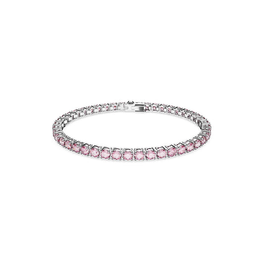 The Swarovski Round Cut Matrix Tennis Bracelet, designed by Swarovski for lasting elegance, features purplish pink stones arranged in a seamless band. It is rhodium plated for added durability and includes a secure rectangular clasp. This sophisticated piece is showcased beautifully on a plain white background.