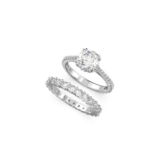 Displayed against a simple background are two stunning rings from the Swarovski Princess Cut Constella Ring Set. The top ring showcases a large central diamond with pavé detailing on the band, while the bottom ring is adorned with a continuous row of evenly sized diamonds.