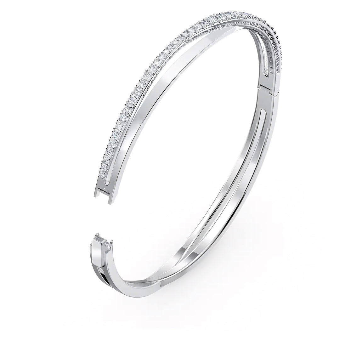 The Swarovski Hyperbola Bangle is a modern, minimalist piece from Swarovski, featuring a sleek silver design with a row of small, sparkling crystals along its curve, set against a white background to emphasize elegance and simplicity.