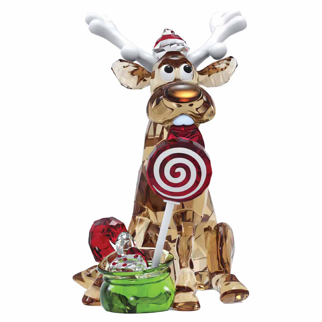 The Swarovski Holiday Cheers Dulcis Reindeer Home Décor is a whimsical crystal figure by Swarovski, featuring a reindeer wearing a Santa hat and antlers while holding a red and white swirled lollipop. In front of this festive collectible sits a small green dish with round red and white candies.