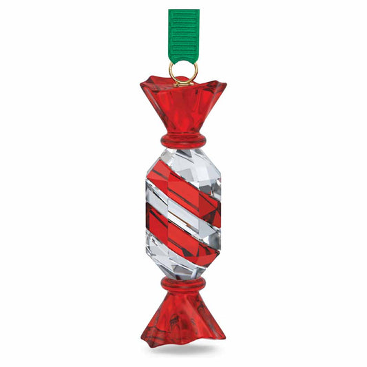 The Swarovski Holiday Cheers Dulcis Crystal Ornament from the renowned brand Swarovski showcases a beautifully crafted glass ornament in the shape of a wrapped candy, decorated with vibrant red and clear diagonal stripes. It is elegantly suspended from a green ribbon with a golden loop, adding charm to your festive setting.