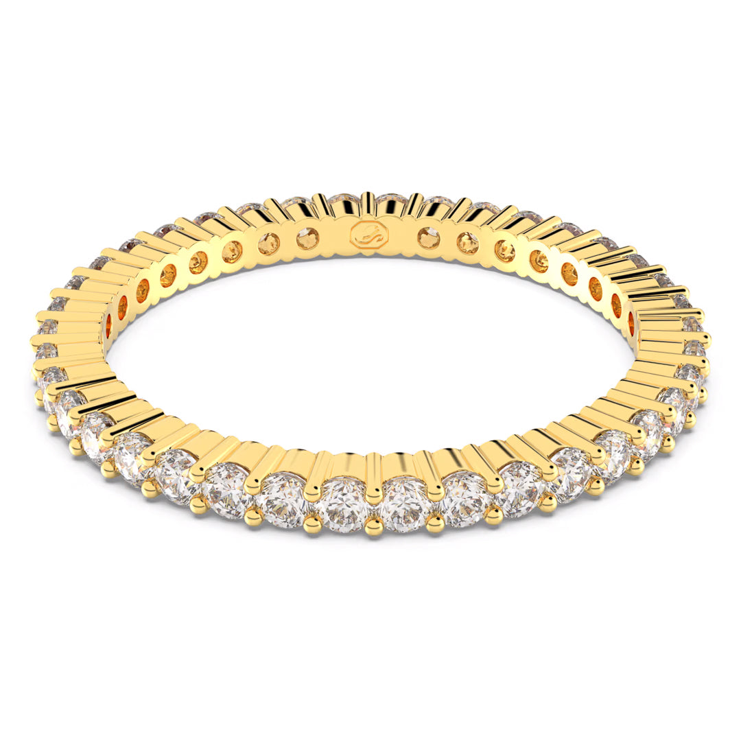 The Swarovski Vittore Ring by Swarovski features a gold-tone finish adorned with shimmering round zirconia that completely encircle the band. Its intricate design beautifully combines the sleekness of gold-tone with clear gemstones, resulting in a luxurious and elegant look.