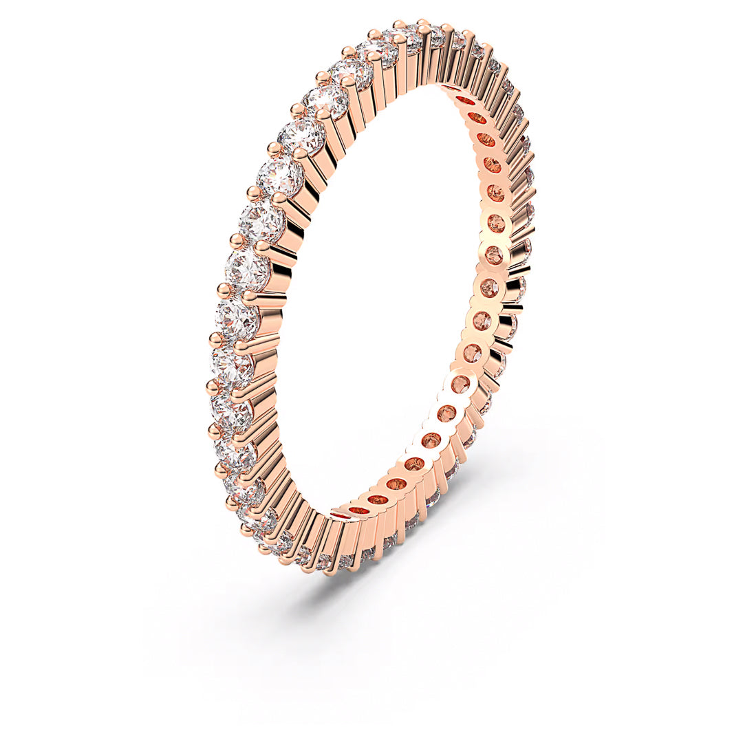 The Swarovski Vittore Ring is a beautifully crafted piece by Swarovski, featuring an elegant rose gold-tone finish and adorned with a continuous band of small, round diamonds. This eternity ring showcases a delicate and sparkling design with a lined texture on the band.