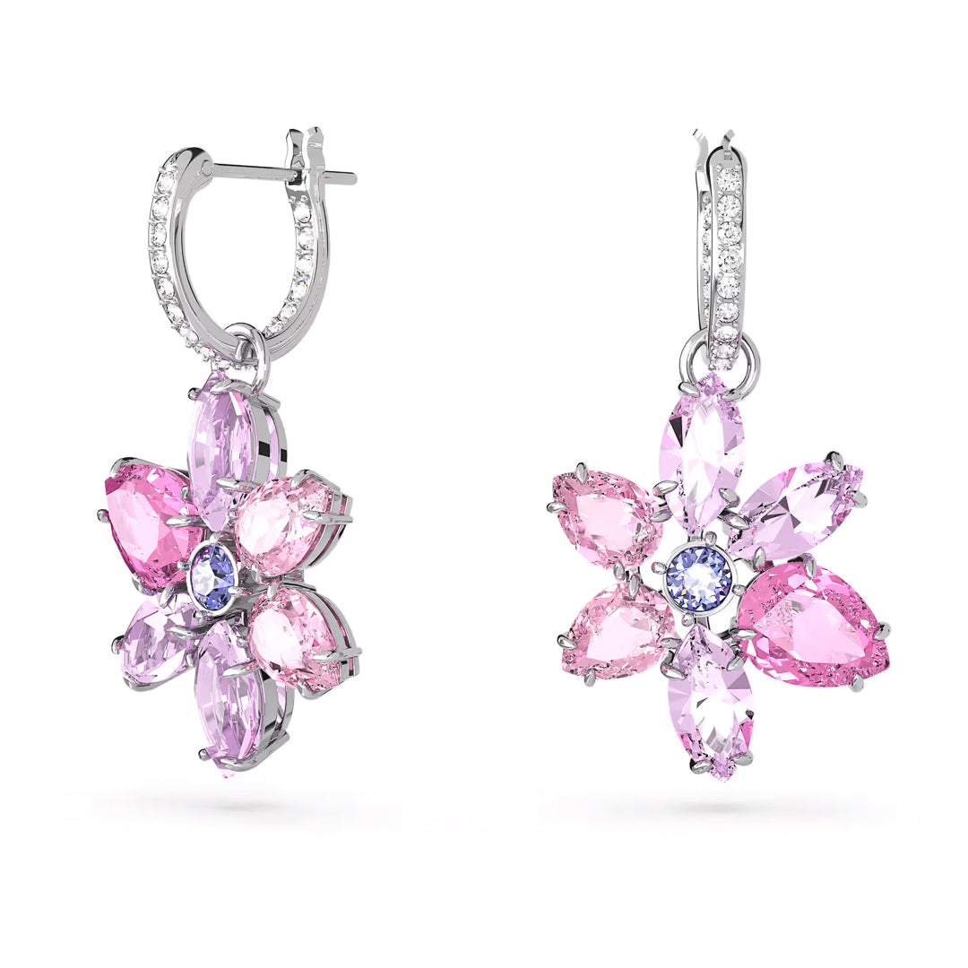 The Swarovski Gema Drop Earrings by Swarovski are rhodium-plated mini hoops featuring a floral design. Each earring is adorned with pink and purple teardrop-shaped stones arranged elegantly around a central blue stone. The hoops are further enhanced with small, clear stones for added sparkle.