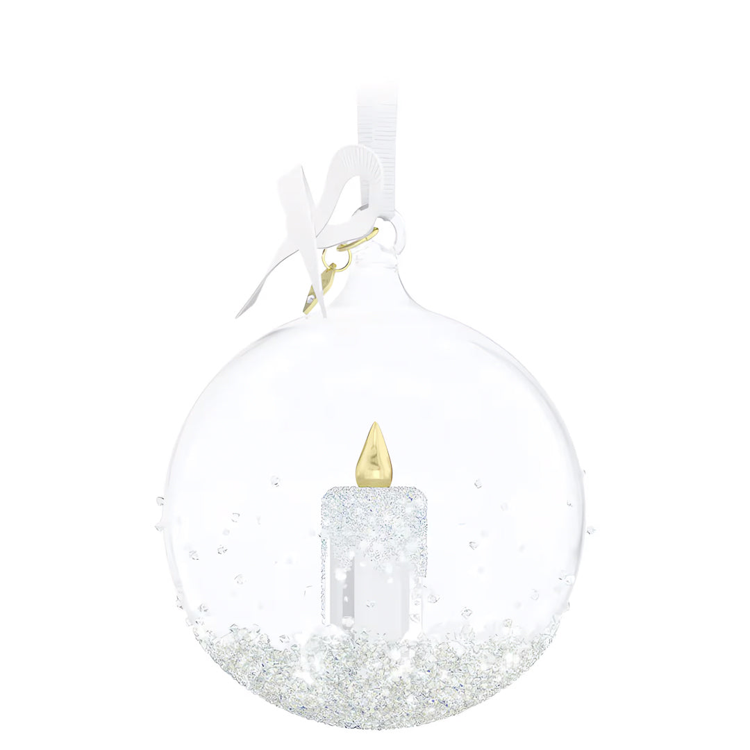 The Swarovski Annual Edition Ball Ornament 2023 Home Décor features a clear glass design adorned with a crystal candle motif inside and topped with a white ribbon. Its lower half glimmers with silver glitter, making it a festive and elegant piece from the renowned Swarovski collection.