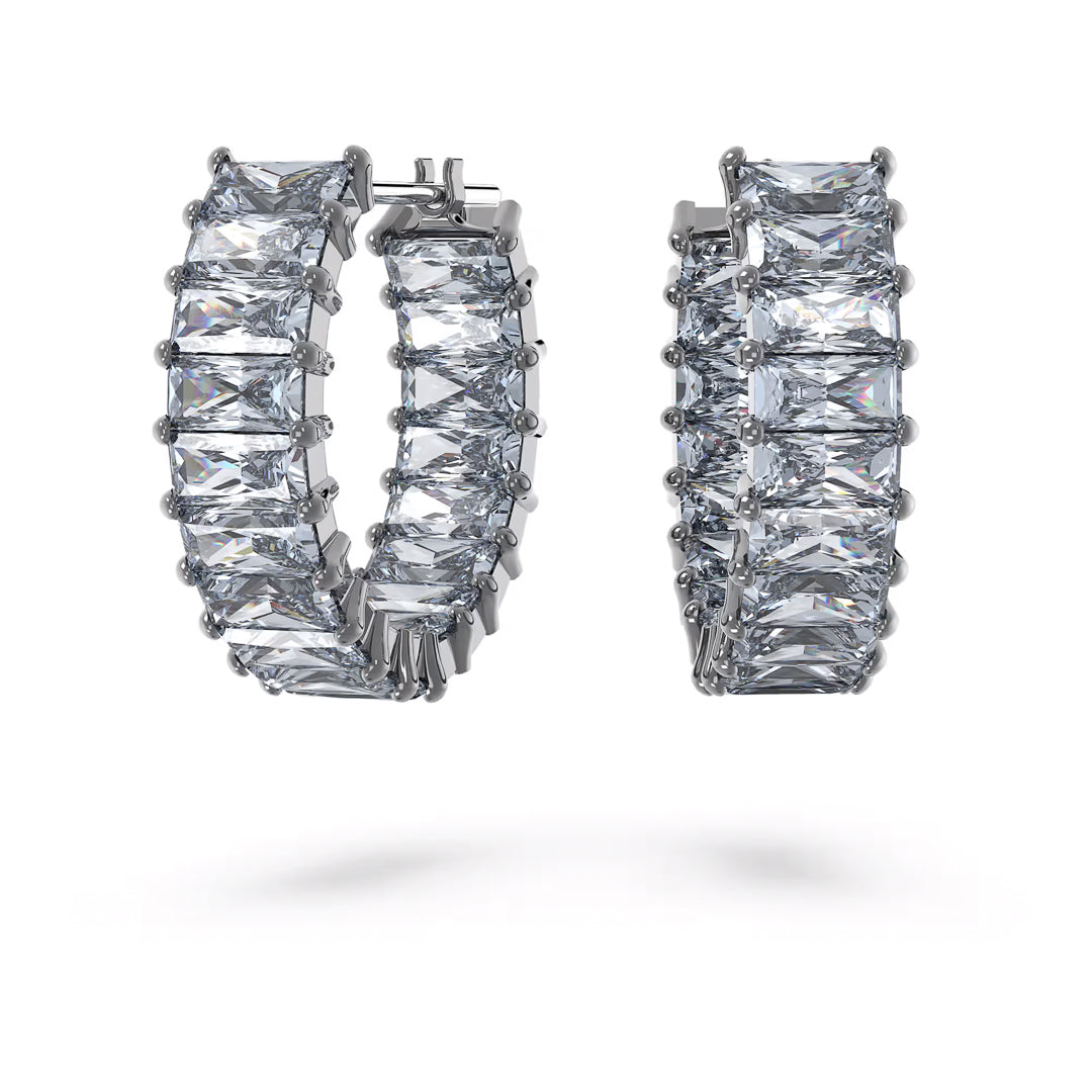 Close-up of Swarovski Matrix Hoop Earrings featuring elegant princess-cut clear gemstones set in shiny silver metal by Swarovski. The earrings are displayed against a plain white background, emphasizing their sparkling appearance.