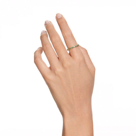 Against a plain white background, a hand with neatly trimmed nails showcases the Swarovski Matrix Ring—a delicate ring from the renowned brand Swarovski—featuring gold-tone plating and adorned with striking Matrix Vittore green stones on the ring finger.