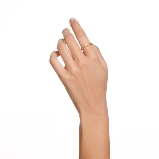 A hand with a light skin tone showcases the Swarovski Matrix Ring, featuring luminescent small beads delicately arranged. The fingers, gently bent against the plain white background, highlight the elegance of Swarovski's gold-tone plating.