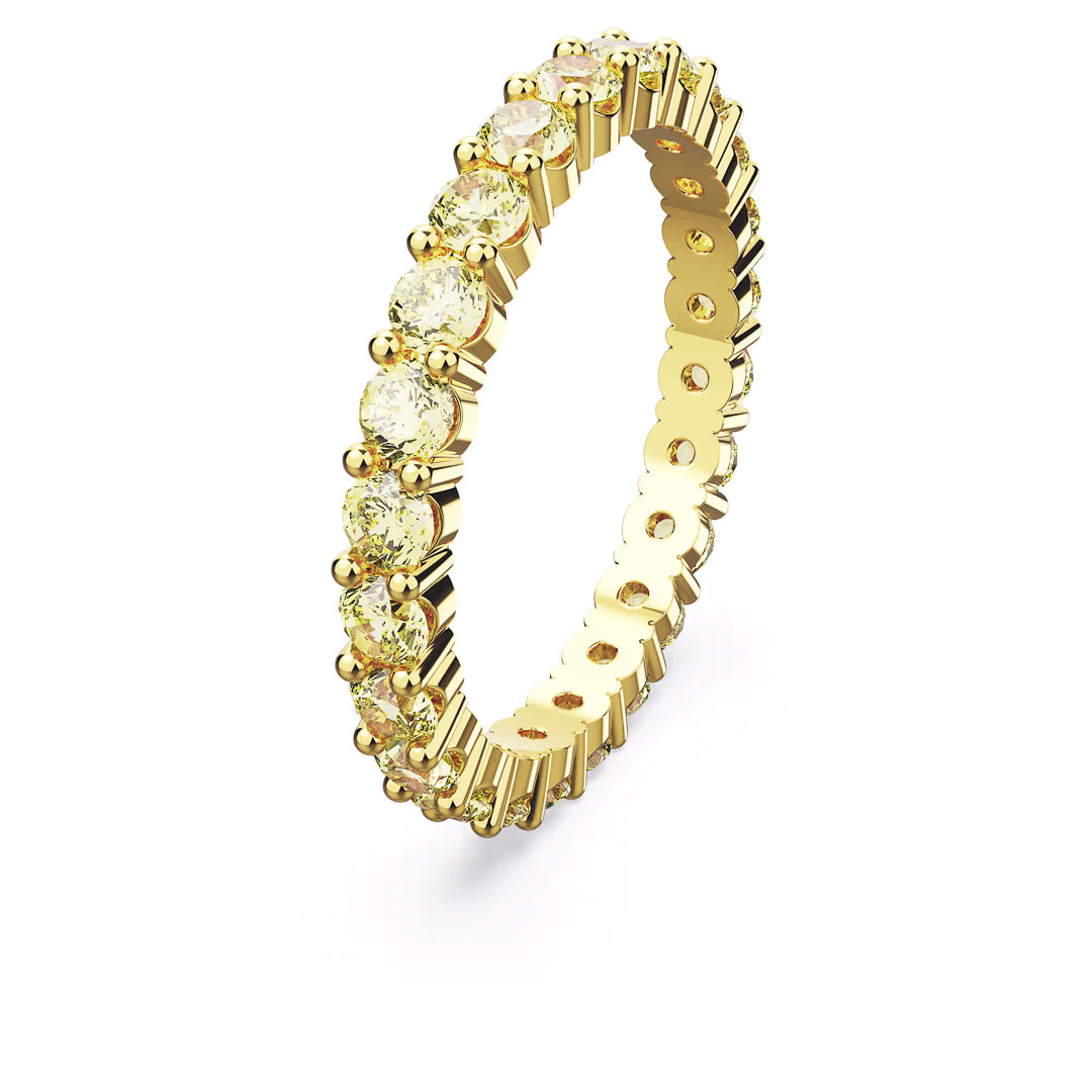 The Swarovski Matrix Ring, by the renowned brand Swarovski, is a luminescent accessory featuring round light yellow gemstones elegantly set in an eternity band style with gold-tone plating. Its intricate detailing and polished finish enhance its luxurious appearance.