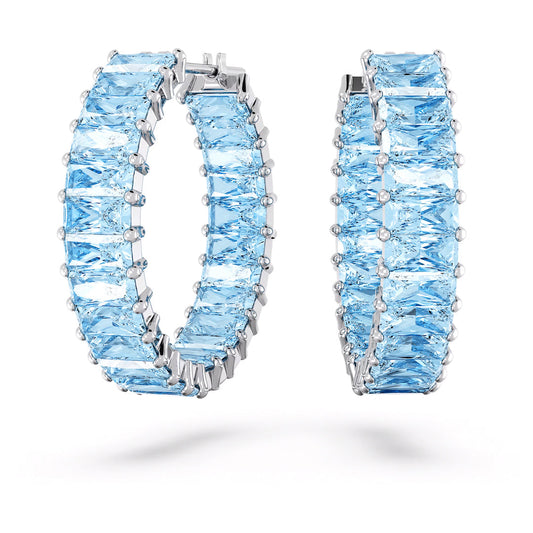 The Swarovski Matrix Hoop Earrings are crafted in rhodium-plated silver and adorned with square-cut aquamarine stones arranged in a continuous pattern, exuding a luxurious and elegant design. These stunning earrings are beautifully presented against a white background.