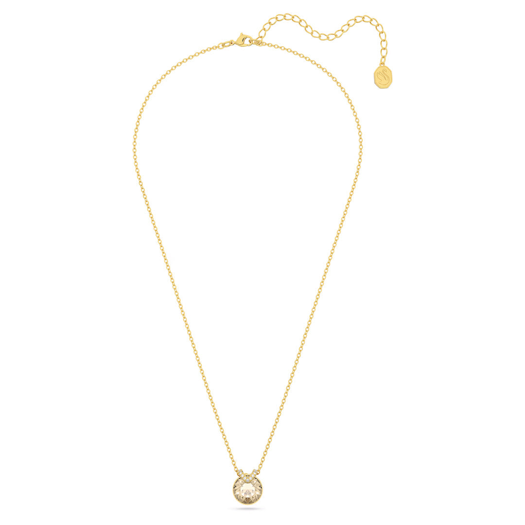 The Swarovski Bella V Necklace Pendant by Swarovski is a gold-tone piece featuring a delicate chain and a captivating center stone in its round, sparkling pendant. The chain is equipped with an adjustable clasp and a small gold tag, while the gemstone enhances the elegance of this minimalist design.