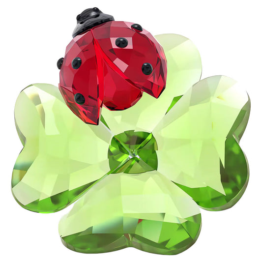 Introducing the Swarovski Idyllia Ladybug Home Décor by Swarovski, a stunning piece showcasing a faceted green four-leaf clover ornament paired with an elegantly designed red ladybug embellished with black dots. This exquisite decoration features a crystal-like appearance that beautifully reflects light.