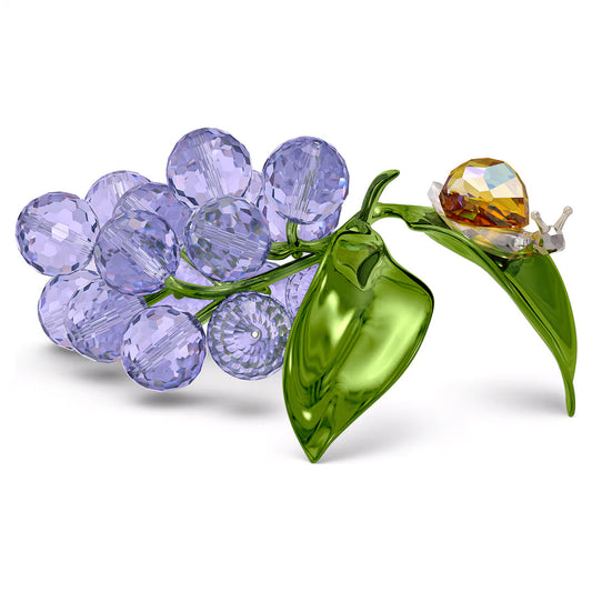 From the Swarovski Idyllia collection, the Swarovski Idyllia Snail and Blueberries Home Décor piece showcases a charming crystal snail perched among a cluster of blue and green crystal leaves, adding whimsy to the exquisite design.
