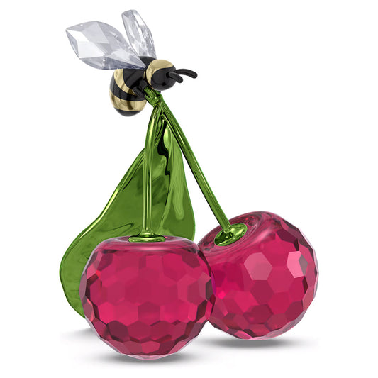A decorative piece from Swarovski, the Idyllia Bee and Cherry Home Décor features two red cherries with faceted surfaces, complemented by a green leaf and stem. An elegantly perched busy bee with transparent wings enhances the intricate design.