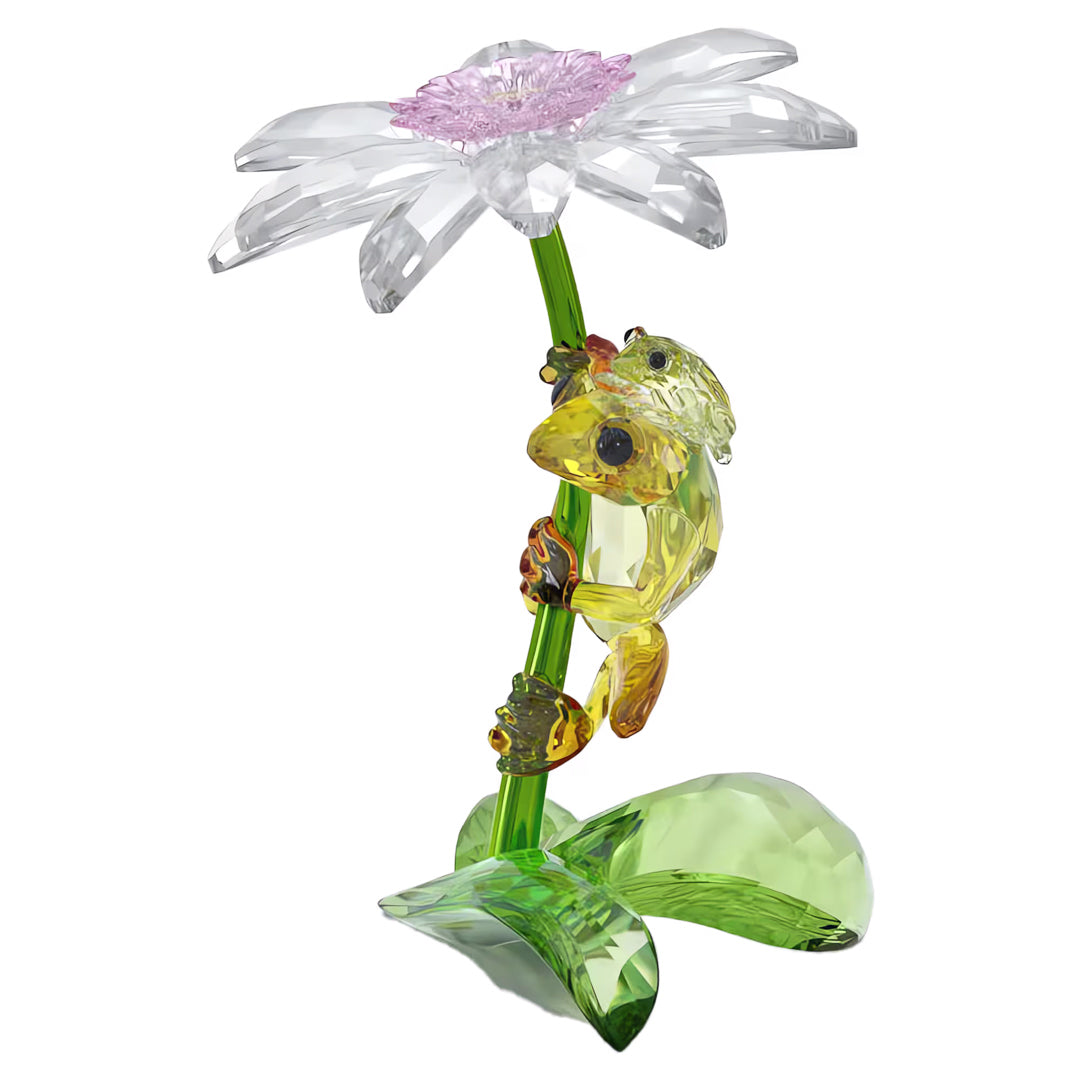 Introducing the Swarovski Idyllia Frogs and Flower Home Décor: a stunning creation by Swarovski that features meticulously crafted green chameleons ascending a stem with a delicate clear and pink flower. This exquisite piece is showcased on an intricately designed green base that mimics the look of leaves, making it an ideal accent to infuse tranquility into your home décor.