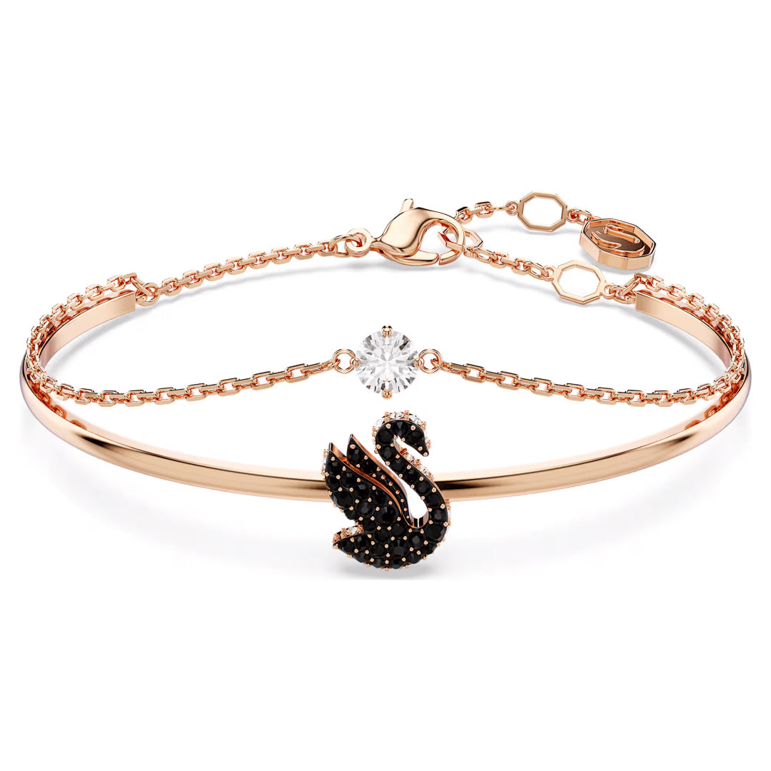 The Swarovski Swan Bangle by Swarovski is an elegant rose gold-tone bracelet featuring a swan motif embellished with small black stones. Its slender chain is highlighted with a dazzling clear Swarovski gemstone and includes an adjustable clasp adorned with hexagonal charms.