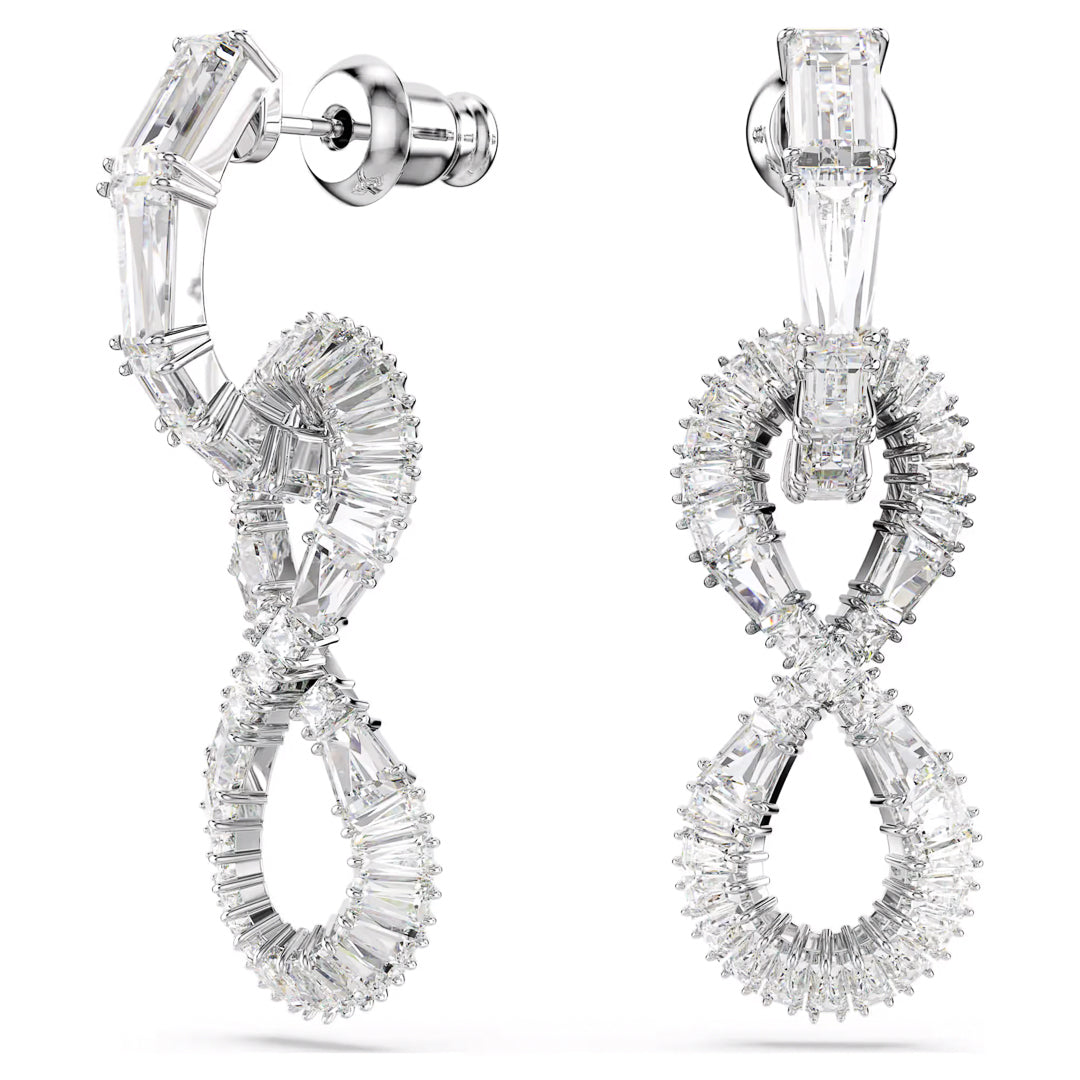 Presenting the Swarovski Hyperbola Drop Earrings by Swarovski, featuring an elegant figure-eight design adorned with clear, sparkling gemstones. Rhodium-plated for enhanced brilliance, these earrings showcase a circular top part that connects to a post stud, while the loops are formed by tapering baguette-cut stones. The result is a luxurious and intricate appearance.