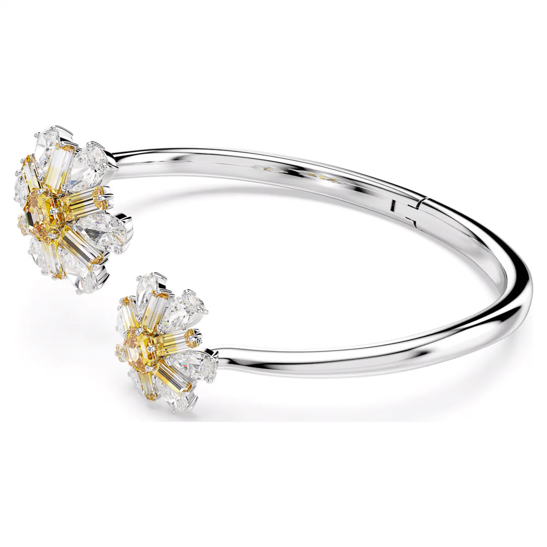 Introducing the Swarovski Idyllia Bangle: a silver bracelet with an open cuff design, showcasing two intricate floral clusters. Each cluster is beautifully embellished with sparkling white and yellow Swarovski Zirconia gemstones, offering a delicate and elegant appearance.