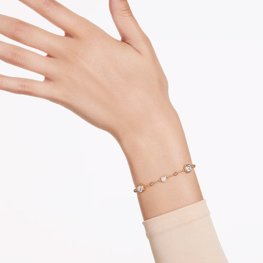 The Swarovski Imber Bracelet, featuring a delicate gold-tone plating and adorned with small round-cut crystals, is elegantly displayed on a person's wrist. The plain white background accentuates the simplicity and sophistication of this exquisite Swarovski jewelry piece.