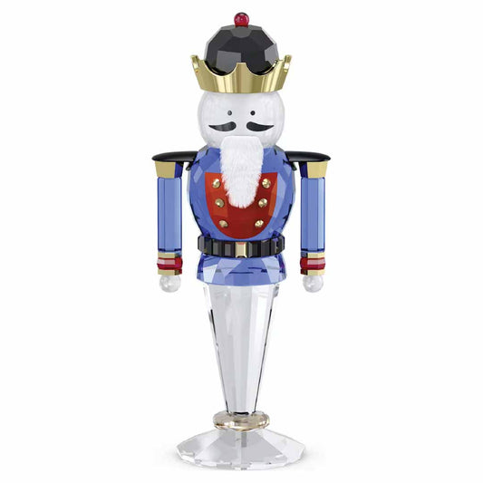 Introducing the Swarovski Holiday Cheers Blue Nutcracker Home Décor, a stunning crystallized figurine from the renowned brand Swarovski. This delightful piece showcases a nutcracker soldier with a white beard, black eyes, and a gold crown. Its attire features a striking blue and red uniform adorned with elegant gold accents. Standing gracefully on a clear base, this exquisite figure is the perfect addition to any holiday decor.