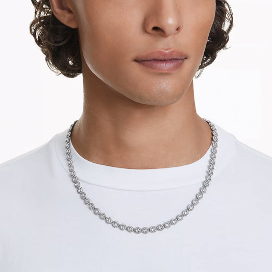 A person is wearing a white t-shirt and the sophisticated Swarovski Una Angelic Necklace, featuring a central crystal. The silver, ruthenium-plated necklace draws attention against the plain white background, highlighting the upper part of the t-shirt.