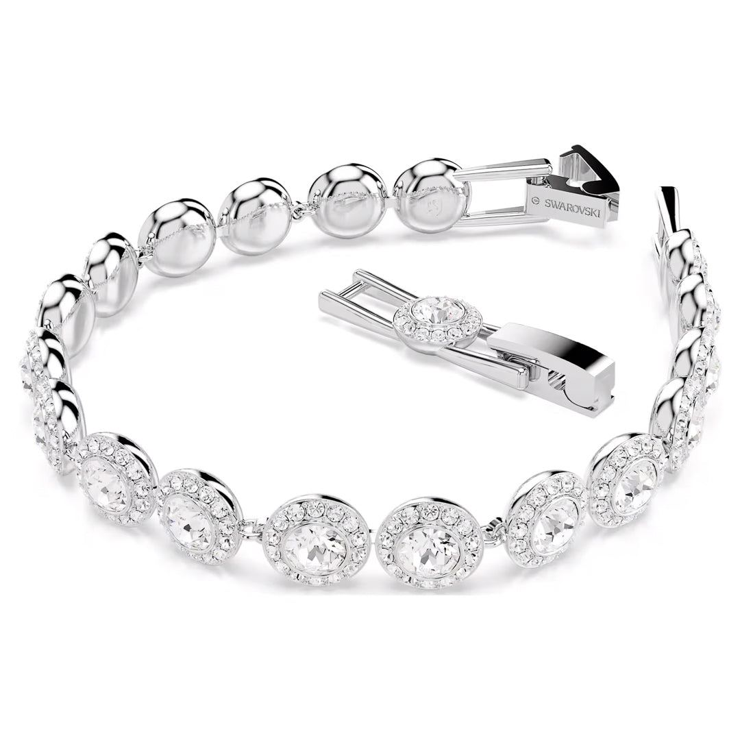The Swarovski Una Angelic Tennis Bracelet is a stunning piece featuring round, sparkling crystal stones arranged in a symmetrical design with a shiny silver finish. Rhodium plated for lasting shine, the bracelet's open clasp showcases its metal link closure with a small central crystal accent. The elegant piece lies flat on a white background.