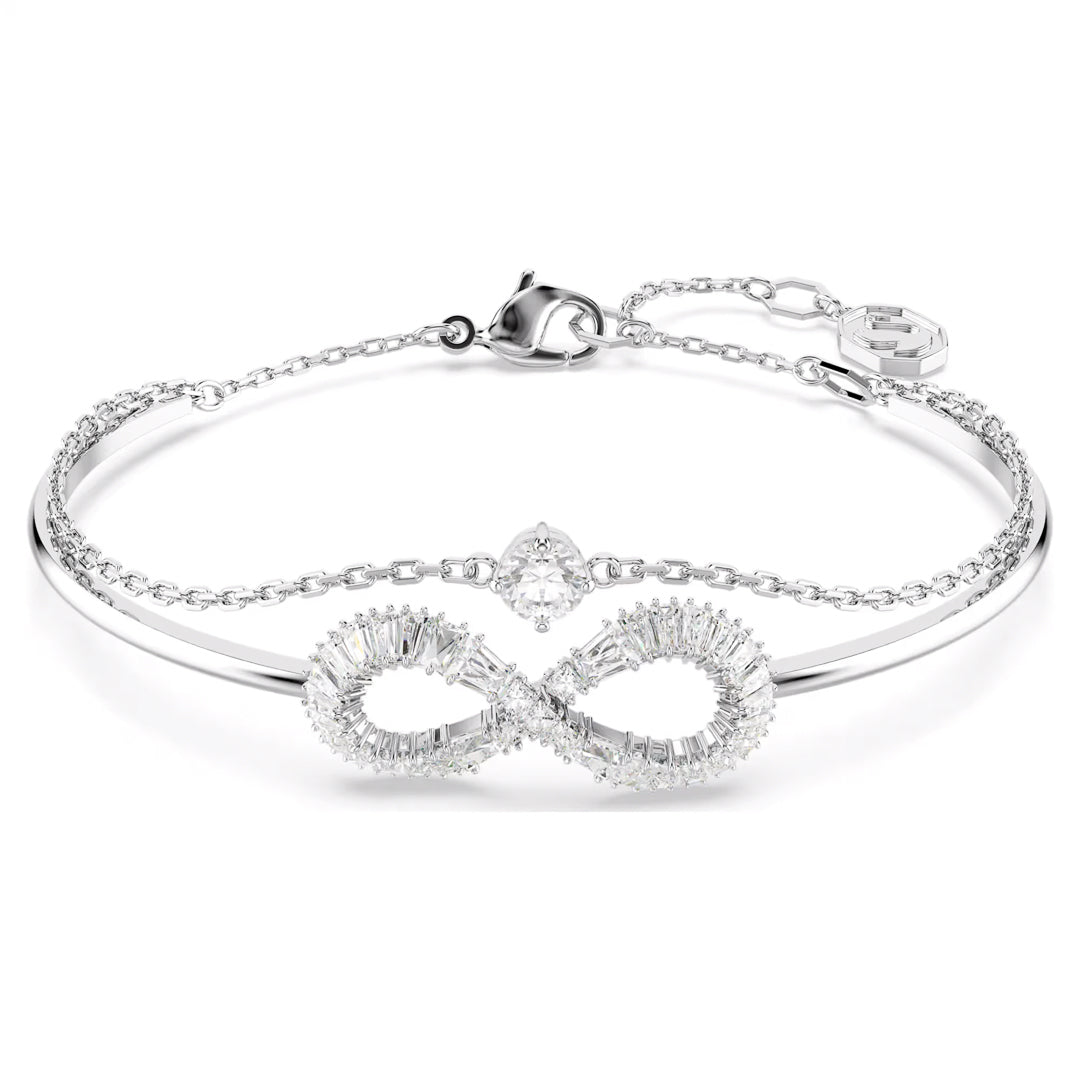Introducing the Swarovski Hyerbola Bangle: a finely crafted bracelet by Swarovski, adorned with an infinity symbol embellished with small Swarovski Zirconia stones. This rhodium-plated silver piece features a delicate chain, accompanied by a secure clasp and an elegant charm. Its sophisticated design exudes elegance and class.