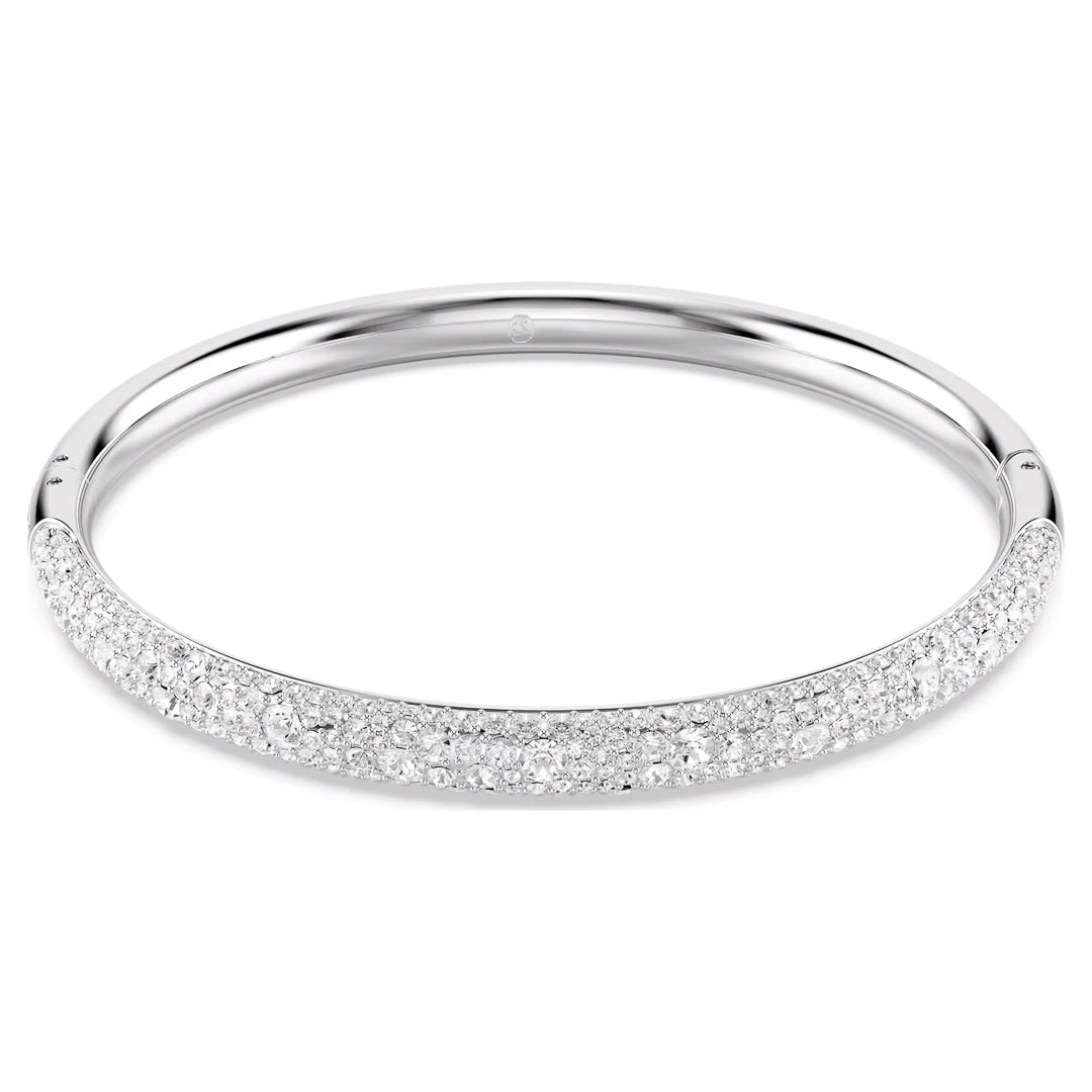 The Swarovski Sublima Bangle is a silver masterpiece from the brand Swarovski, featuring clear round crystals in an elegant design with a sleek, rounded shape. These dazzling gems adorn the front half of the rhodium-plated band, creating a luxurious and polished look against a plain white background.