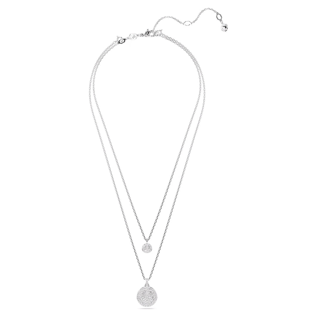The Swarovski Sublima Layered Necklace Pendant by Swarovski is a rhodium-plated design featuring two chains of varying lengths. Each chain is adorned with a shimmering layered pendant, including a larger round, textured pendant on the longer chain. The necklace also features an adjustable clasp for flexible styling.