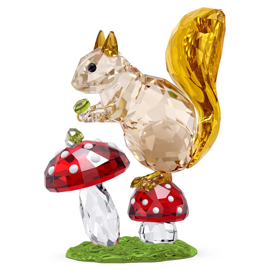 As part of the Swarovski Idyllia collection, the Swarovski Idyllia Squirrel and Mushrooms Home Décor piece showcases a crystal squirrel with a golden tail holding a green nut, perched on red and white spotted mushrooms atop a green base, all crafted in a faceted crystal design.