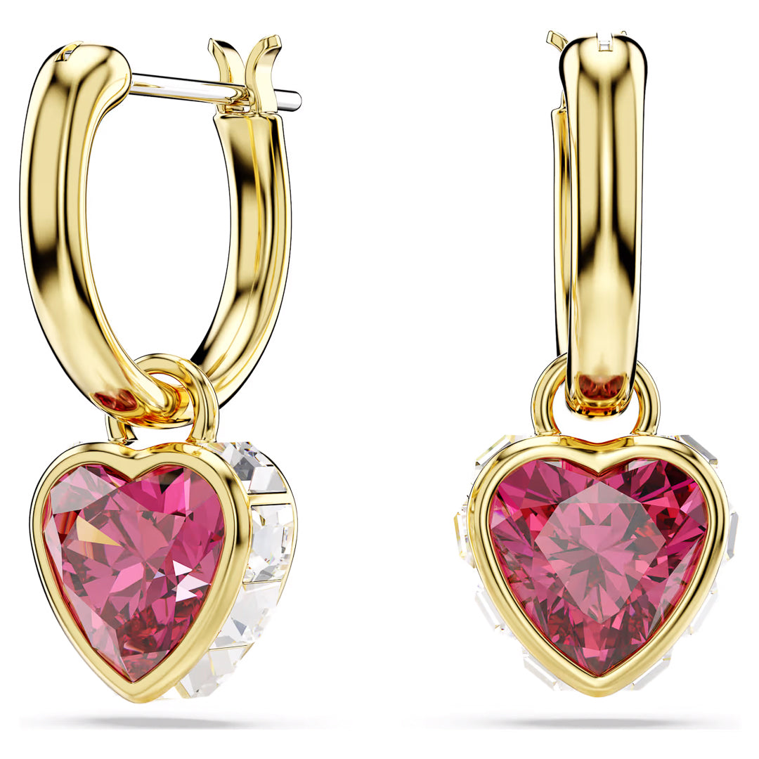 Introducing the Swarovski Chroma Heart Drop Earrings by Swarovski, featuring an elegant pair of gold-tone hoops adorned with a heart-shaped motif embellished with pink Swarovski Zirconia gemstones. Each hoop displays a small pink heart pendant accented with clear stones, offering a luxurious and stylish appearance.