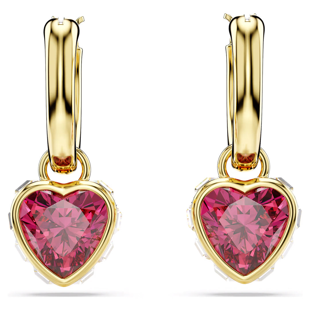 Introducing the Swarovski Chroma Heart Drop Earrings by Swarovski - a stunning pair of gold-tone hoops featuring an elegant heart-shaped motif adorned with faceted pink gemstones. These earrings dazzle beautifully as they catch the light with their intricate settings.