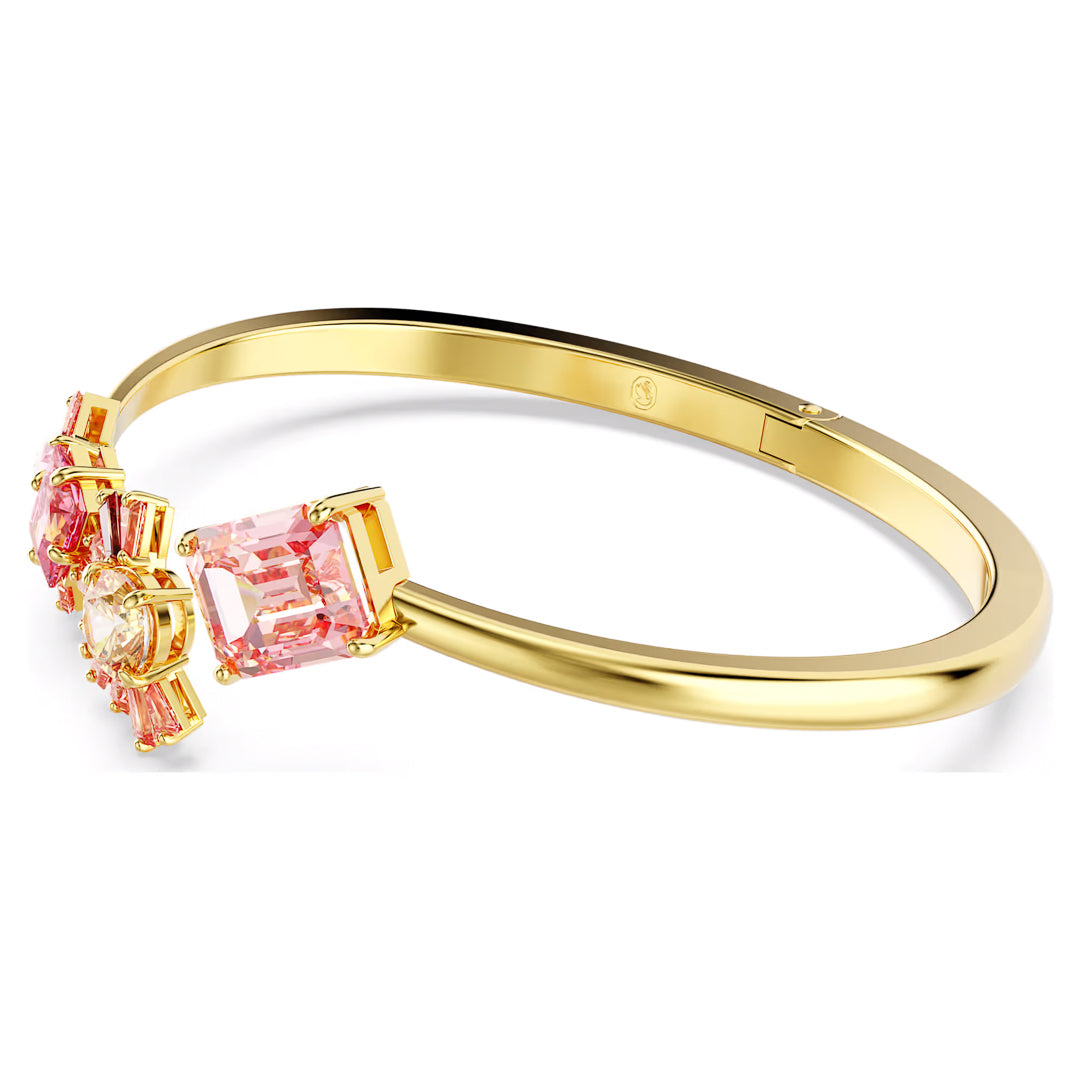 The Swarovski Gema Bangle by Swarovski highlights a central clear Swarovski Zirconia surrounded by large pink rectangular gemstones, capturing the elegance of cherry blossoms. Smaller pink stones contribute to the charm of this sleek, modern accessory.