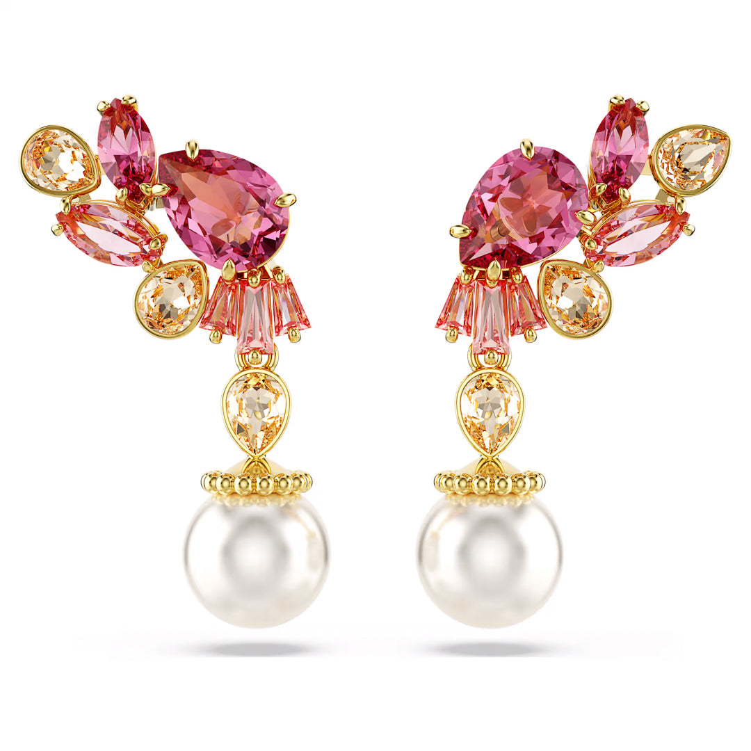 A pair of Swarovski Gema Drop Earrings, crafted in gold and featuring an array of pink and orange gemstones in various shapes, is adorned with large, lustrous white pearls at the bottom. Inspired by cherry blossoms, they capture the delicate beauty of nature.