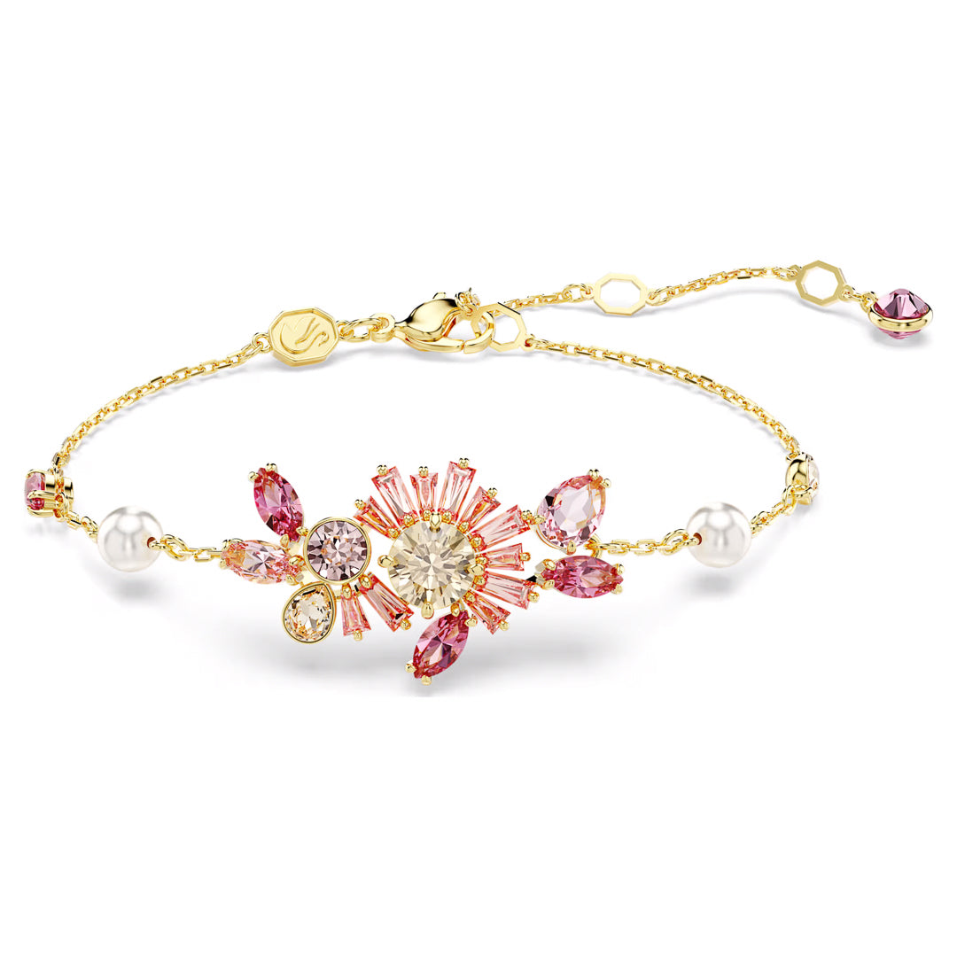 The Swarovski Gema Bracelet is a delicate gold piece adorned with a floral arrangement of pink and clear crystals, enhanced by Swarovski Zirconia and small Crystal Pearls. It features an adjustable chain with a decorative end charm for the perfect fit.